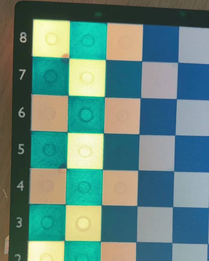 My 3D-printed prototype board. Amber and cyan lights glow under the squares of the a and b files.